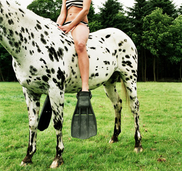 A woman in a bikini gracefully sitting on a horse, radiating confidence and allure.