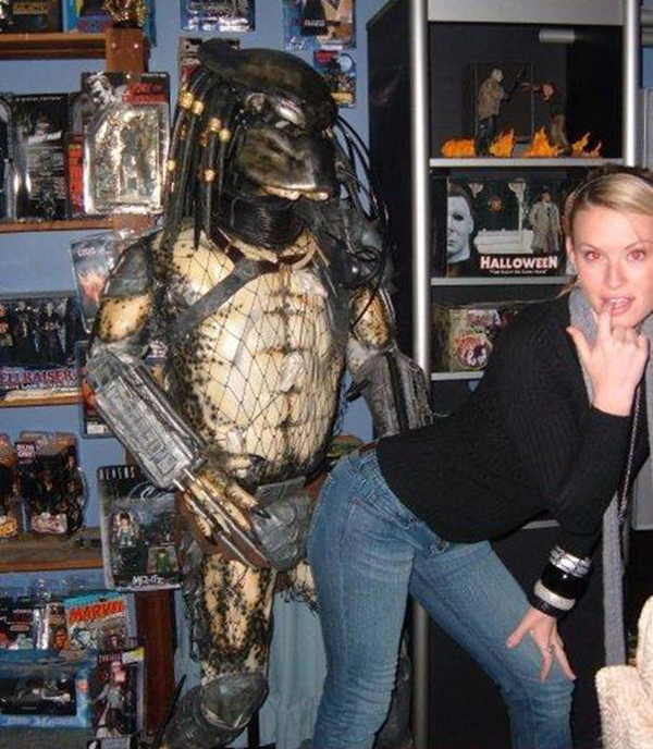 A woman gracefully poses next to a predator statue, exuding confidence and allure.