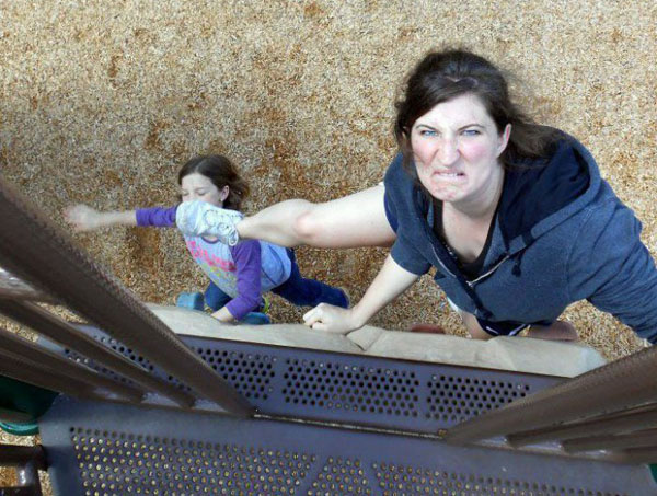 A woman and a child on a slide at a playground.