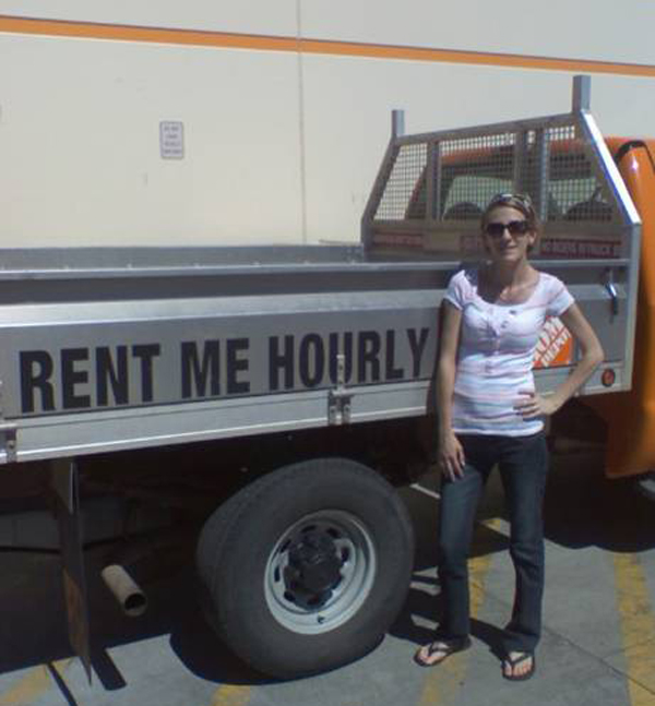 A woman standing next to a truck that says rent me hourly, but I Would Date You But...