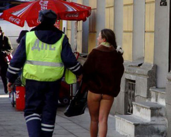 A naked woman walking down the street with a police officer.
