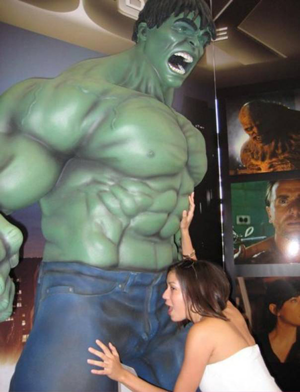 A woman posing next to an incredible Hulk statue, embodying the phrase 