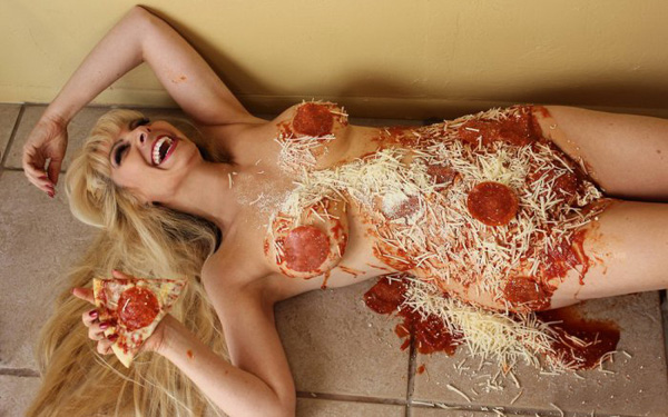 A woman laying on the floor, covered in pizza and laughing uncontrollably.
