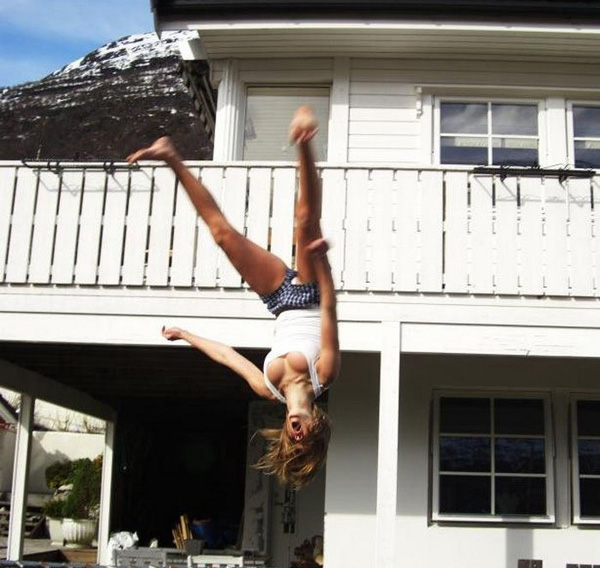 A girl doing a flip in front of a house, showcasing her impressive acrobatic skills.