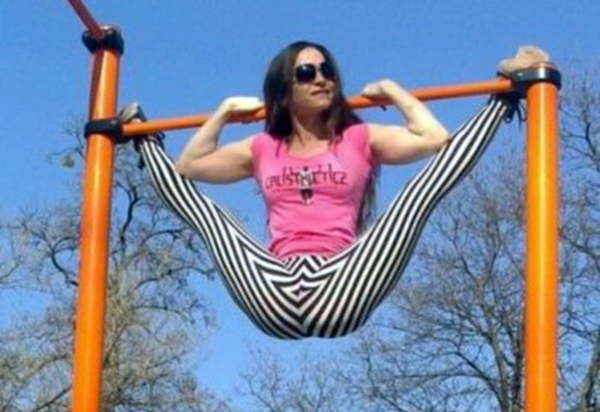 A woman gracefully performing pull ups on an orange bar with strength and determination.