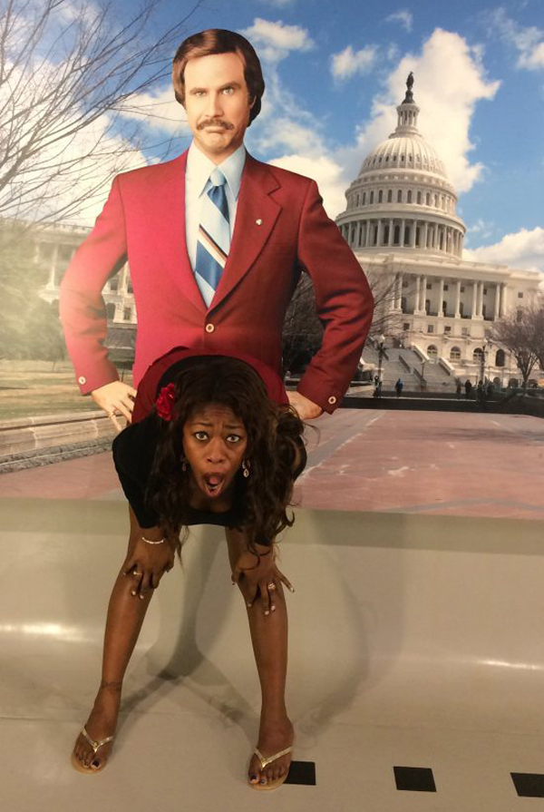A woman posing in front of a statue of an anchorman.