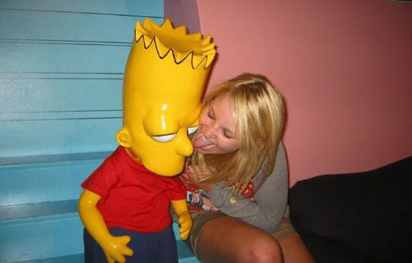 A woman is affectionately kissing a Simpsons statue, showcasing her fondness for the popular animated series.