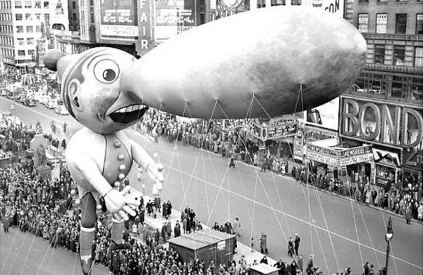 The Macy's Day Parade balloon gracefully floats over a crowd of people.
