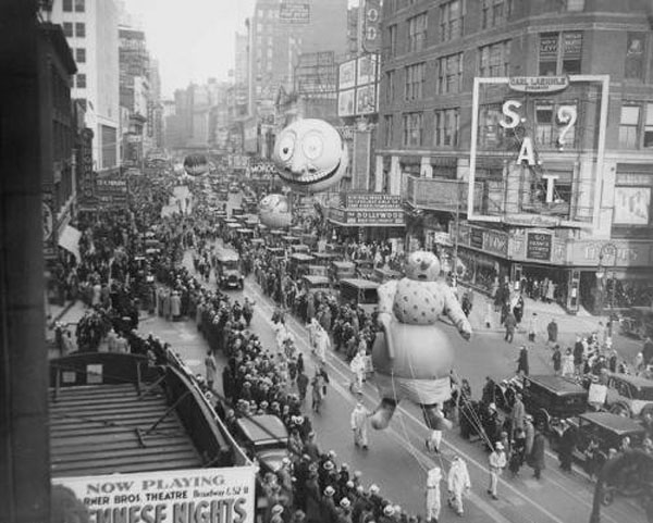 A black and white photo of a parade with balloons