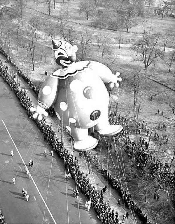 Macy's Day Parade starts out with a large balloon floating over a crowd of people.