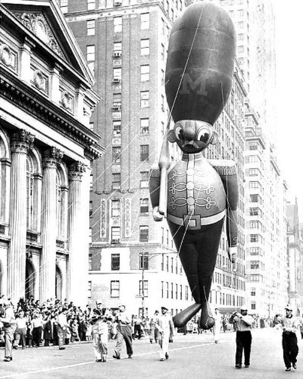 An **old** photo of a large **balloon** flying over a city.
