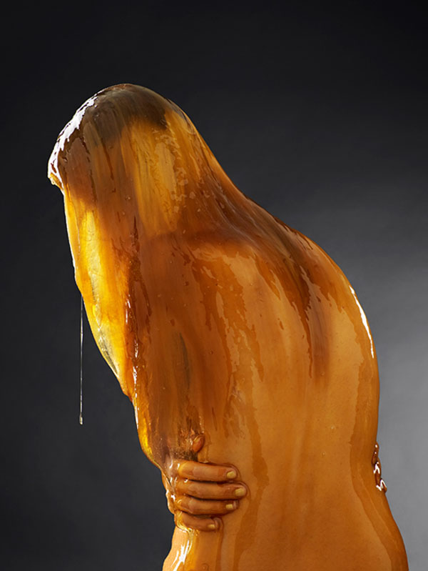 A naked woman completely drenched in honey.