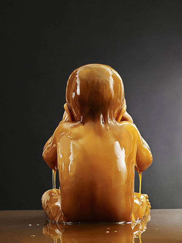 A sculpture of a naked baby submerged in honey.