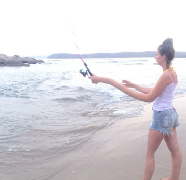 A girl is flying a kite on the beach, creating a picturesque panorama at this scenic location.