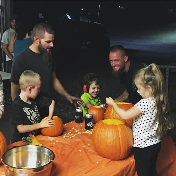 A group of people carving pumpkins at a table for Radass Daily.