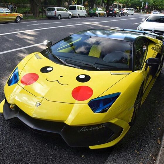 A yellow car with a ridiculous pokemon face painted on it.