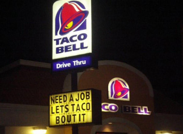 A taco bell sign is lit up at night, showcasing a pucking punny display.
