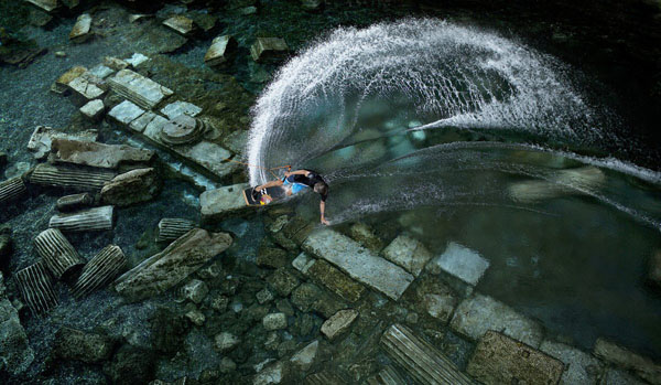 An aerial view of a person water skiing in a river, capturing the exhilaration of the moment.