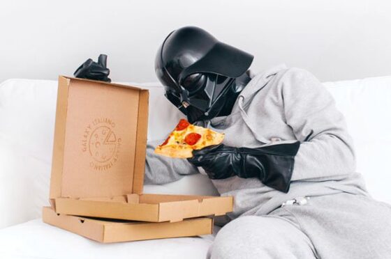 The Daily Life of Darth Vader wearing a mask while enjoying pizza.