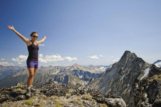 A woman standing on top of a mountain with her arms outstretched, showcasing her triumphant victory.