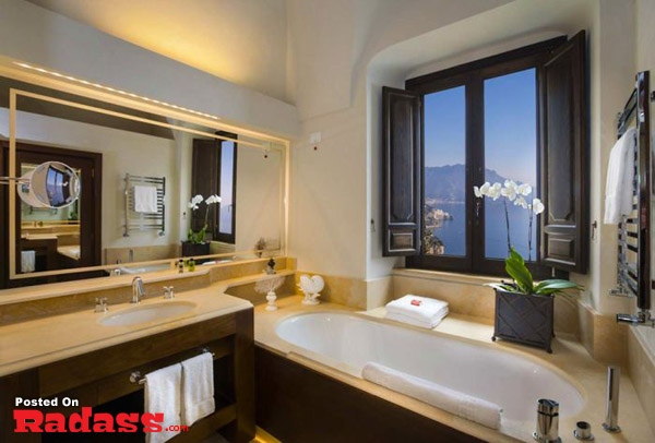 A bathroom with a large window overlooking the sea, just living the dream.