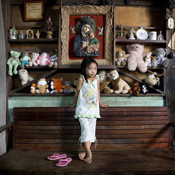 A young girl standing in front of a wooden bench with stuffed animals, inspired by "Toy Stories" by Gabriele Galimberti.