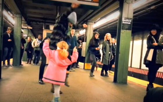 A little girl is starting a hoedown in a NYC subway stop.