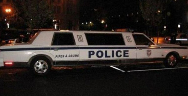 A WTF police limo is parked on the street at night.