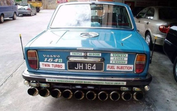 A bizarre car with an excessive number of pipes on the back.