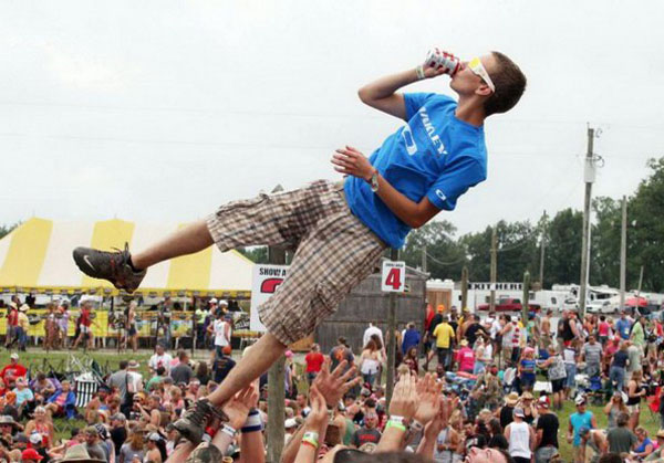 A man in blue jumps into the air at a music festival, capturing the exhilarating spirit of the Weekend.