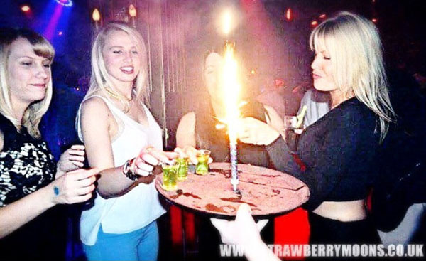 Weekend Confessions: A group of girls holding a lit up cake in a nightclub.