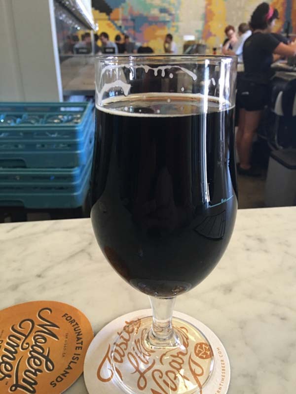 A glass of dark beer sitting on a counter.