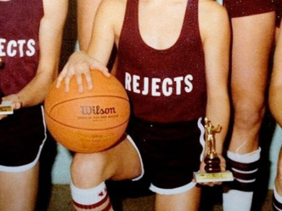 An old photo of a girl holding a basketball and a trophy.