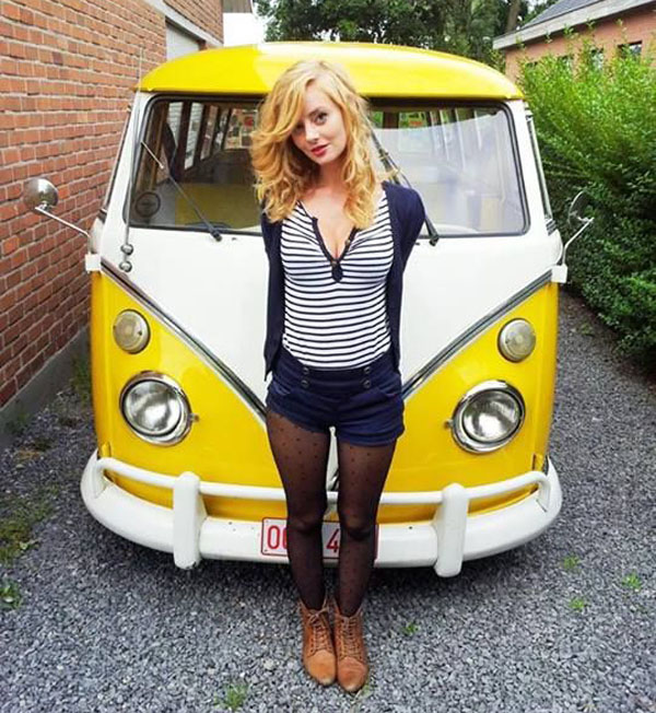A blonde babe posing with a yellow VW bus.