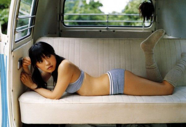 A young babe lounging on the bed of a VW van.