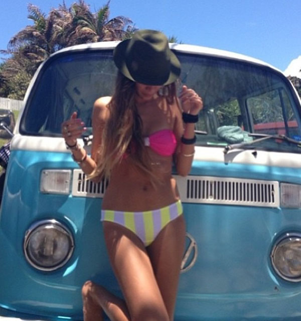 A babe rocking a hat and bikini poses alongside a classic VW bus.