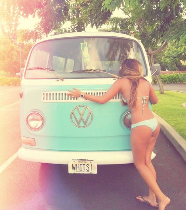 A bikini-clad babe posing next to a VW bus.