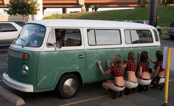 A group of babes are posing in front of a dubs-inspired VW bus.