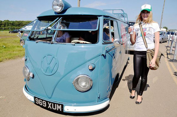 A babe posing with a blue VW bus.