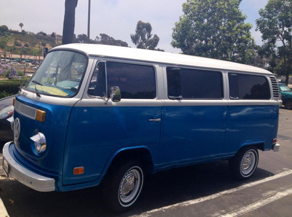 A cool blue VW bus parked in a lot.