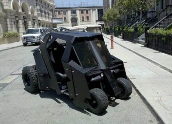 The batmobile is parked on the side of the street, showcasing one of the most cool ass cars out there.
