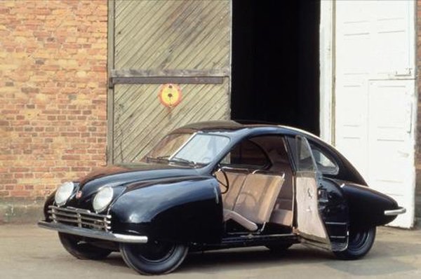 A cool black car with its door open parked in front of a garage.