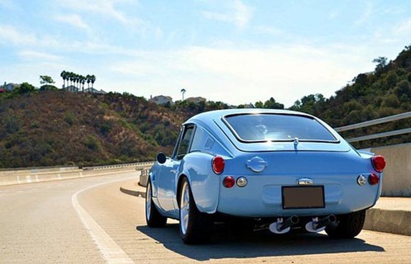 A sports car is parked on a highway, yup it's just a cool blue!