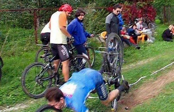 A group of people face planting while watching a group of people riding bikes.