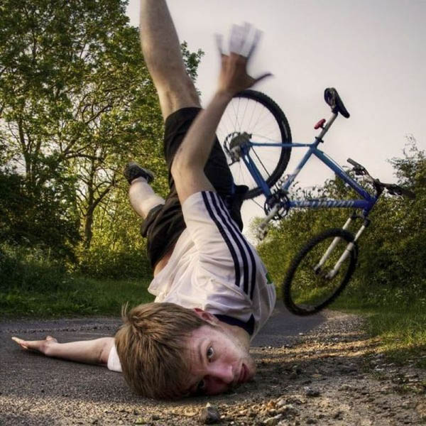 A boy face plants on the ground while holding a bicycle.