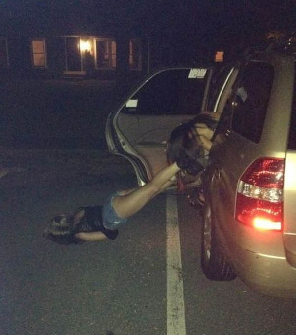 A woman is face planting on the ground in front of a car.