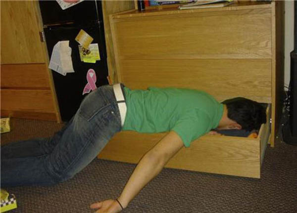 A man face-plants on top of a desk.