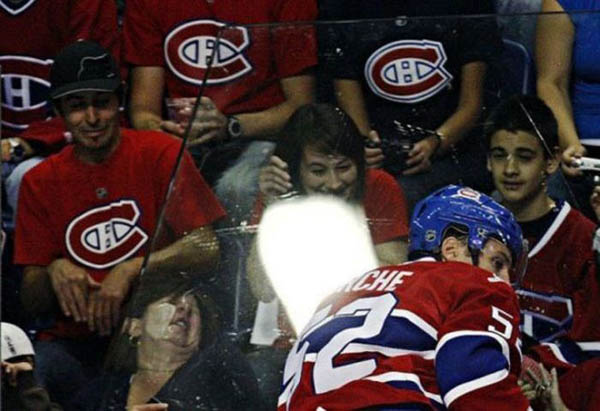 A hockey player is being hit by a puck and face plants during a game.