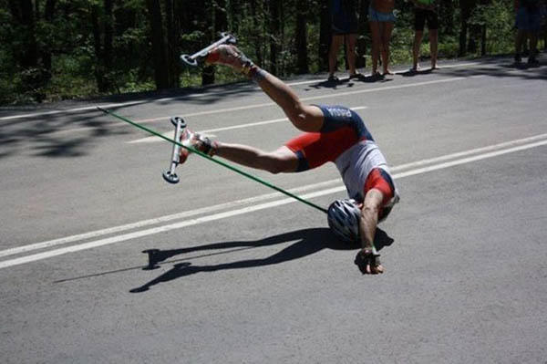 A man on a skateboard doing a flip on the road, face planting.