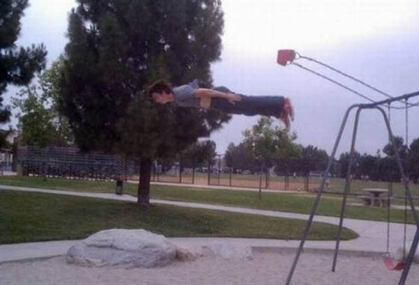 A boy jumping off a swing in a park, occasionally face planting.